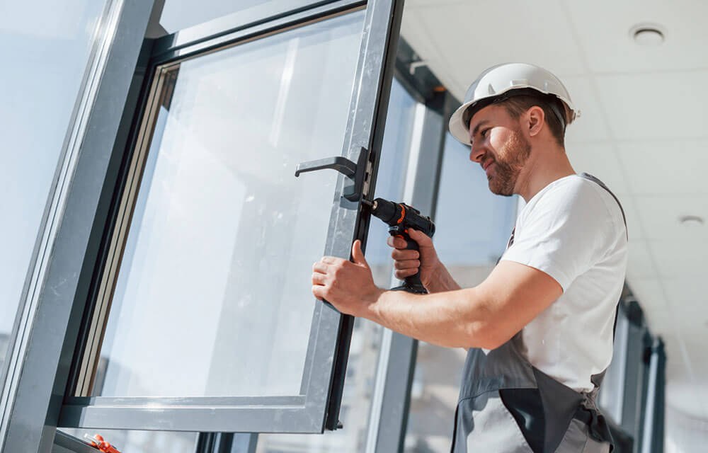Technik pracuje na okenní klice a kování